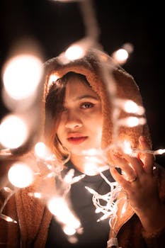 Enchanting portrait of a woman in a hood surrounded by glowing fairy lights.