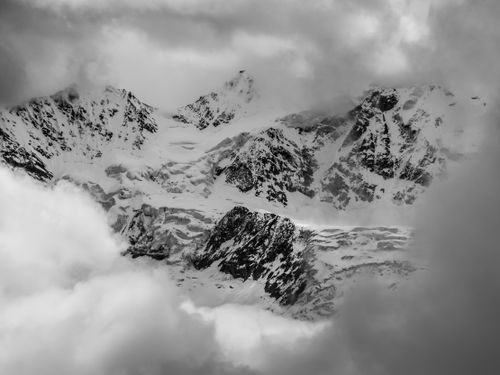 Free Explore the dramatic snowy peaks of the Swiss Alps emerging through moody clouds. Stock Photo