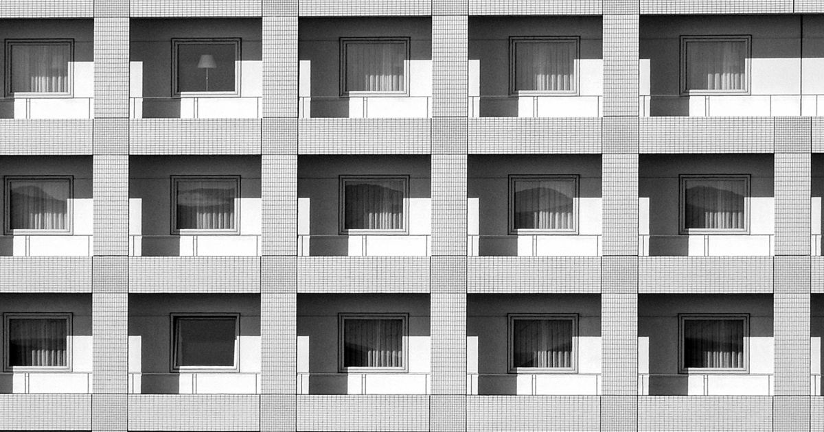 同じ形の窓とベランダが縦横に並ぶ集合住宅の外壁