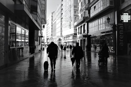 Grayscale Photo of People Walking in Between Buildings