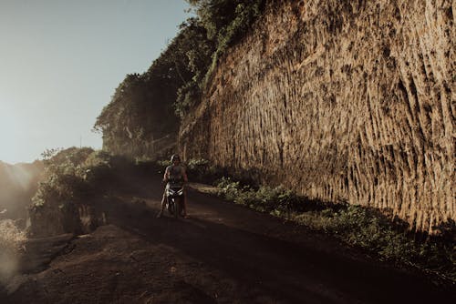 Man Riding a Scooter on Dirt Road 