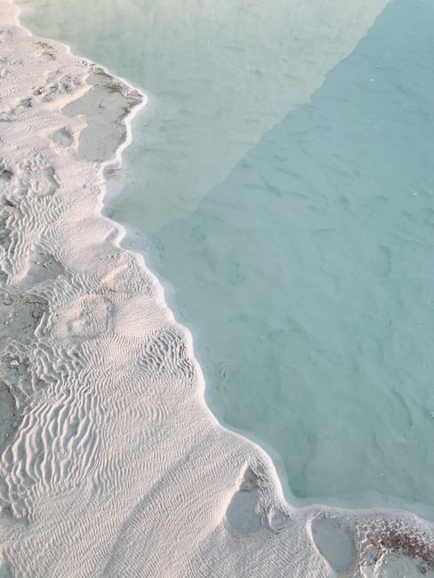 A tranquil aerial shot showcasing the seamless blend of sandy beach and turquoise sea.
