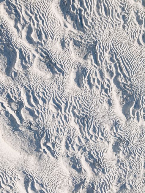 Aerial view of white mineral formations in Pamukkale, Turkey, showcasing unique textures and patterns.