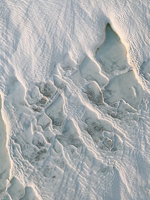 Aerial view of intricate snowy textures on a rocky surface, creating abstract patterns.