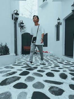 Young man strolling through a modern courtyard with unique stone flooring, showcasing urban fashion.