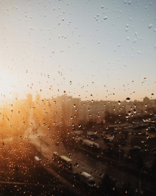 Sunlit raindrops on a window with Minsk cityscape in background, offering a serene view.