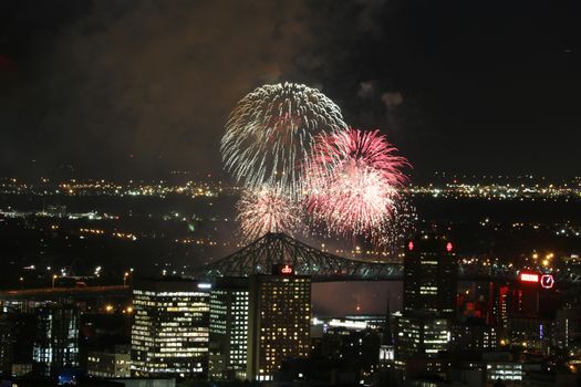 Dazzling fireworks light up the night sky over Montreal with iconic skyline and bridge view.
