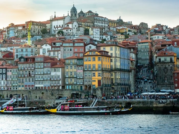 Scenic view of Oporto's historic riverside with colorful buildings and boats at sunset.
