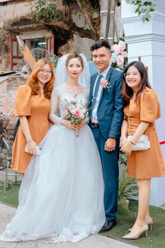 Bride and groom with bridesmaids in elegant attire celebrating outdoors.