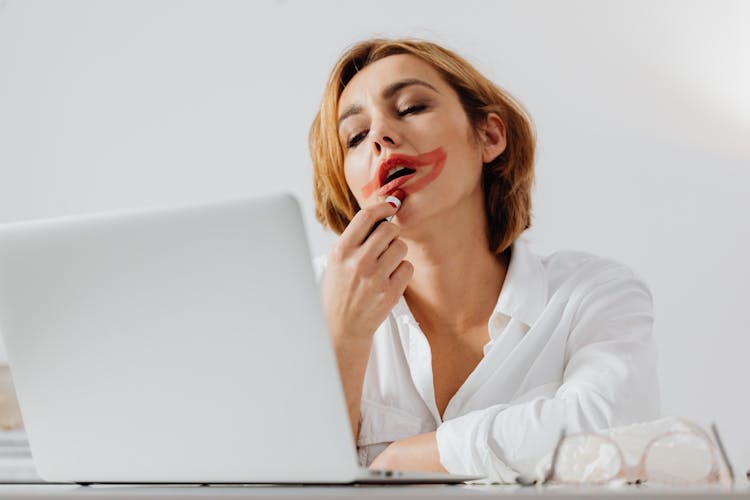 Woman Smearing Lipstick On Her Face While Working