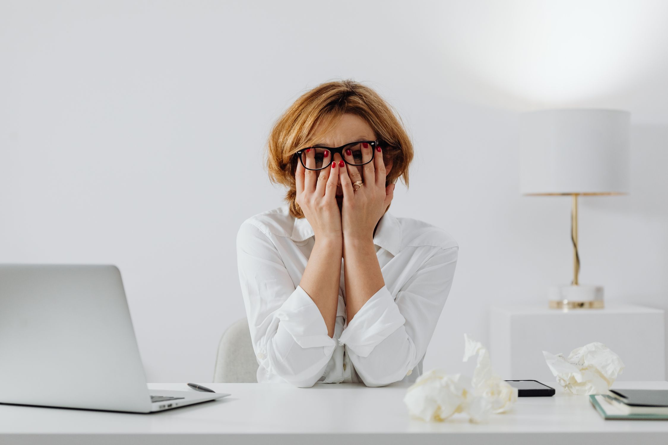 Mulher com as mãos na cabeça expressando sinais de estresse e sobrecarga emocional no trabalho