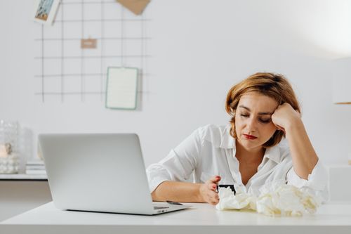 Free Exhausted woman working from home, surrounded by tissues, illustrating remote work challenges while feeling unwell. Stock Photo