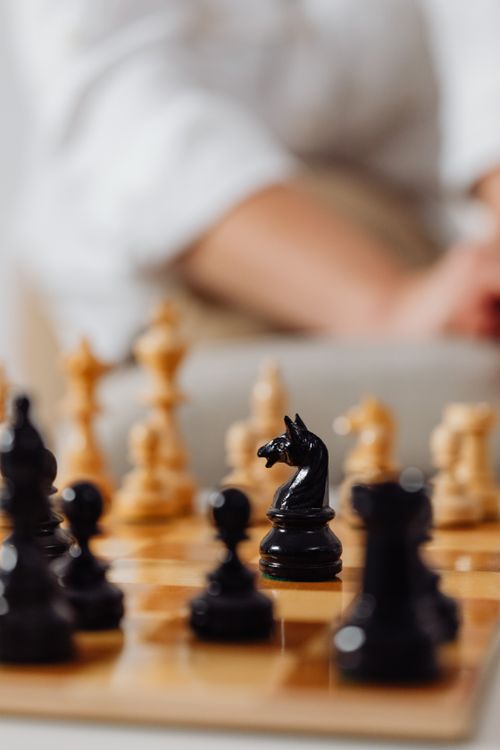 Free Artistic close-up of a chessboard featuring a black knight piece surrounded by blurred chess pieces. Stock Photo