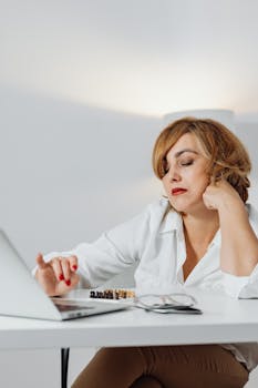 A woman sitting at a desk using a laptop, focused and engaged in work.