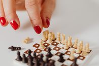 Person With Red Manicure Holding Chess Pieces