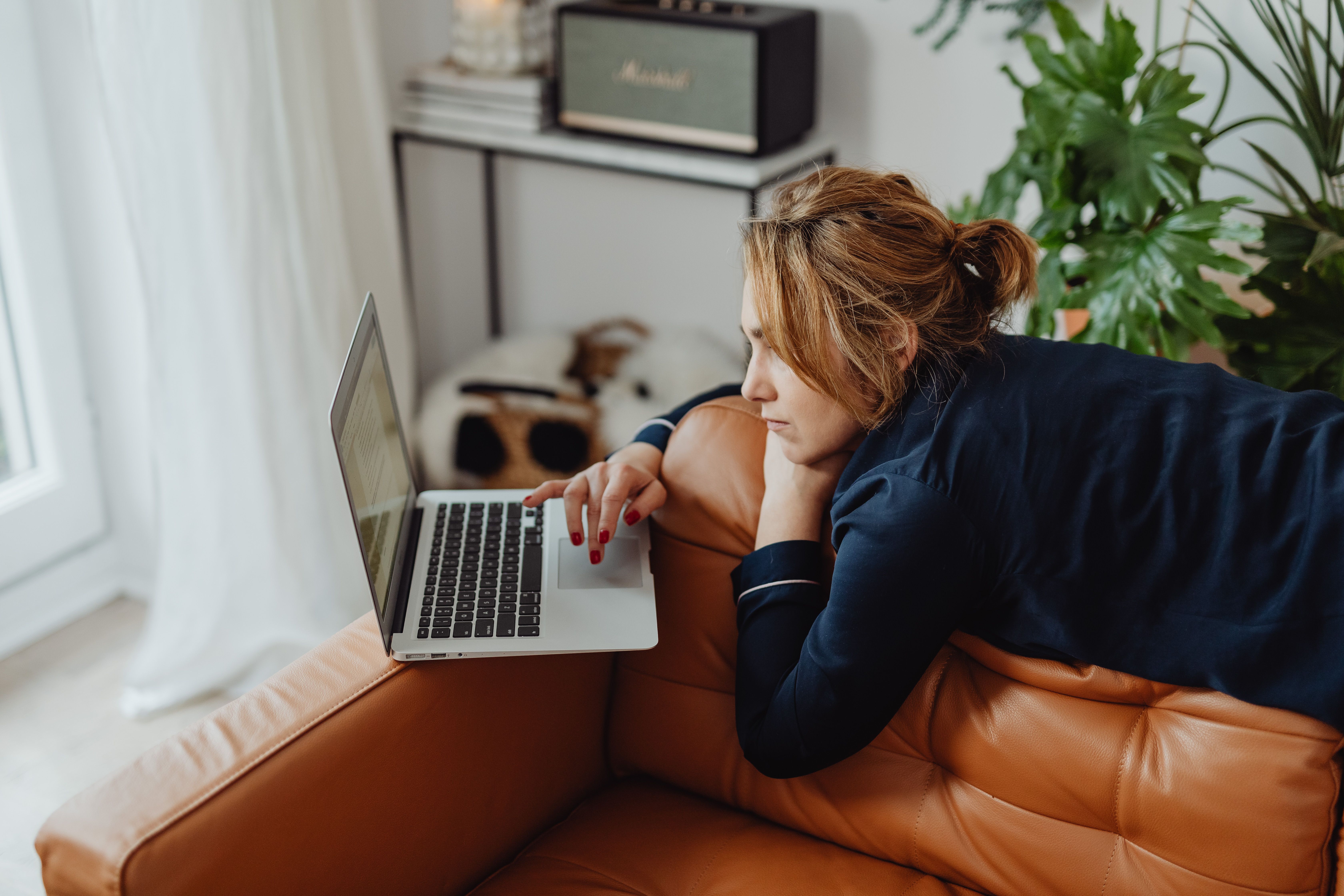 A person relaxing on a couch with a laptop, looking peaceful and productive, not stressed