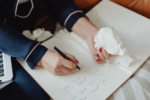 Person with Red Nails Writing on a Notebook