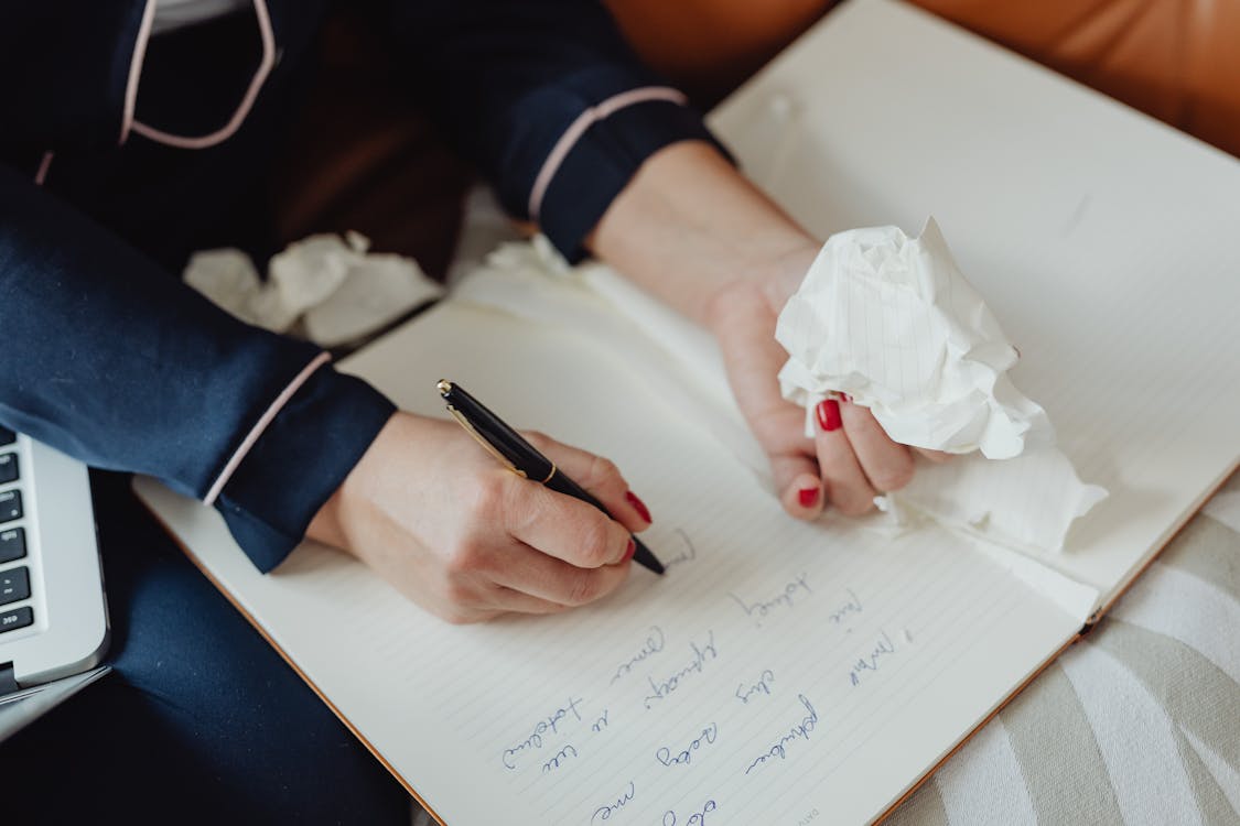 Person with Red Nails Writing on a Notebook with a fountain pen