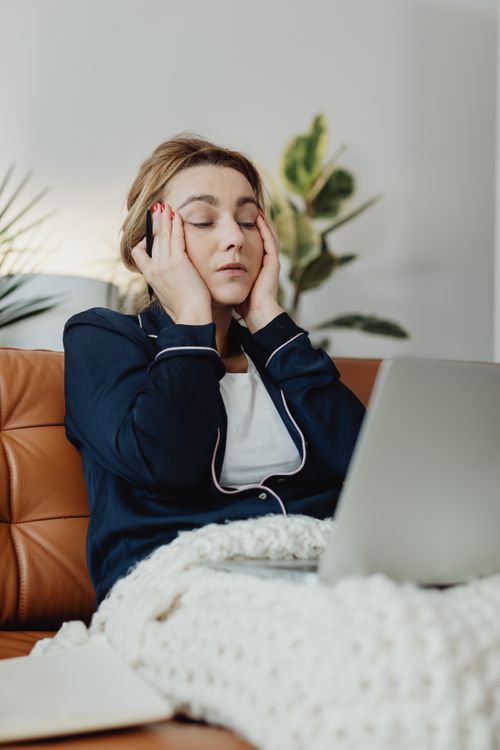 Free Caucasian woman in pajamas relaxing on couch with laptop, showing a calming indoor scene. Stock Photo