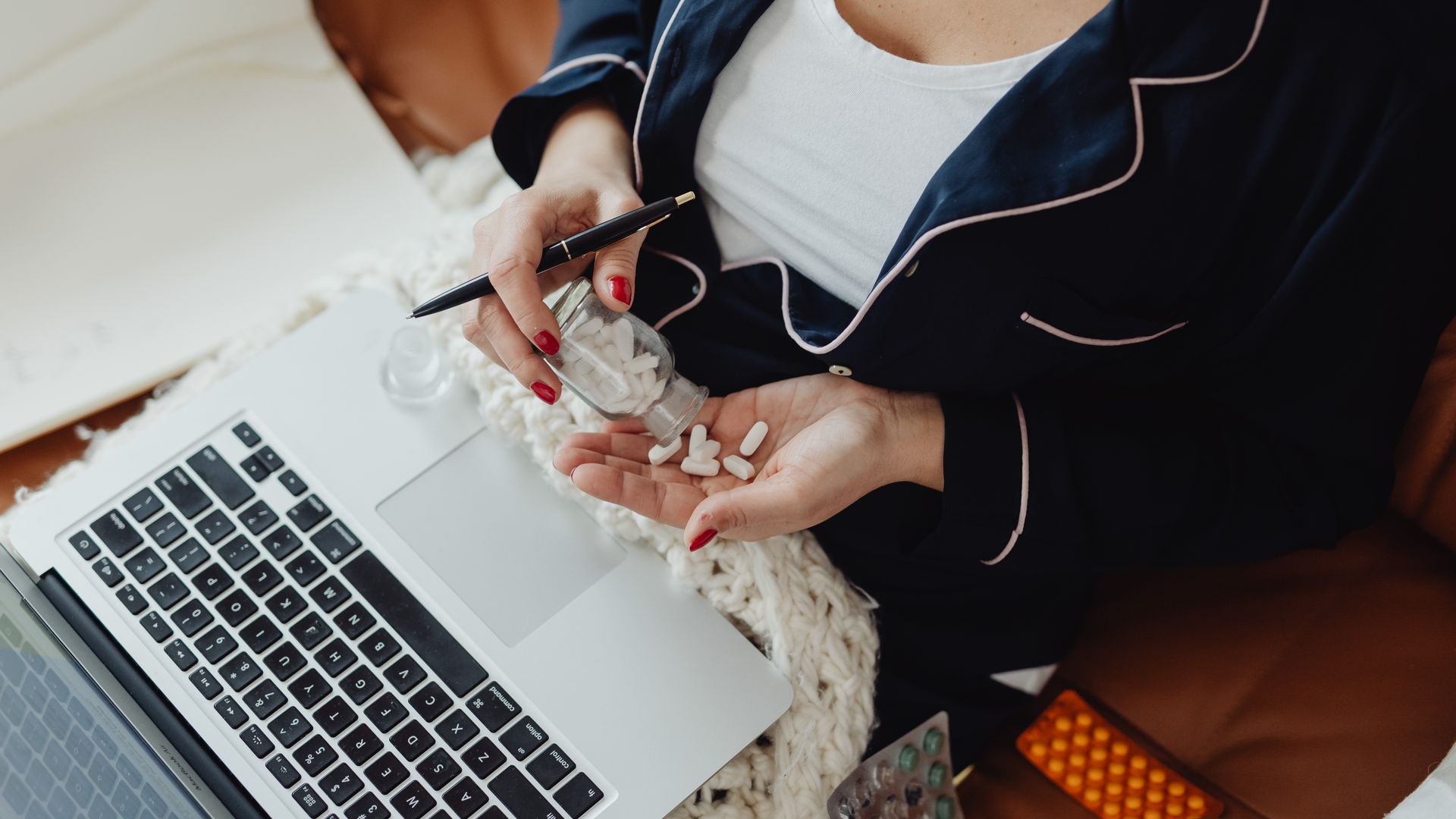 Modafinil for Freelance Writers: Enhancing Productivity Close-up of a woman in pajamas holding pills next to a laptop, illustrating remote work and health care at home — modafinil for freelance writers