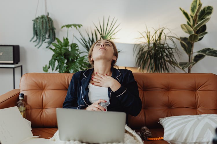 A Woman Swallowing Medicine While Sitting On Couch