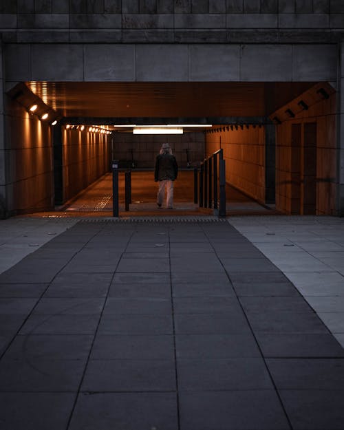 Person Walking on Gray Concrete Tunnel