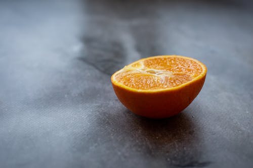 Half of ripe juicy orange placed on black table in kitchen in daylight