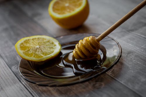 Honey dipper placed on saucer with lemon slice