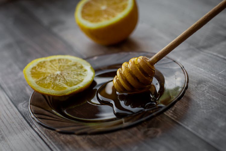 Honey Dipper Placed On Saucer With Lemon Slice