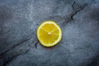 Top view ripe sour lemon slice placed on dark gray cracked background in studio