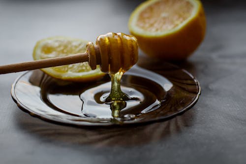Honey dipper above saucer with lemon