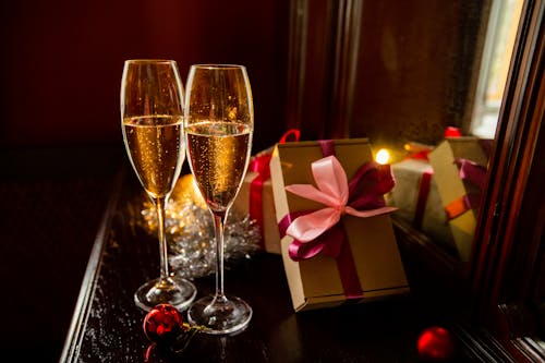 Composition of glasses of champagne placed on table near presents and festive decorations during Christmas celebration