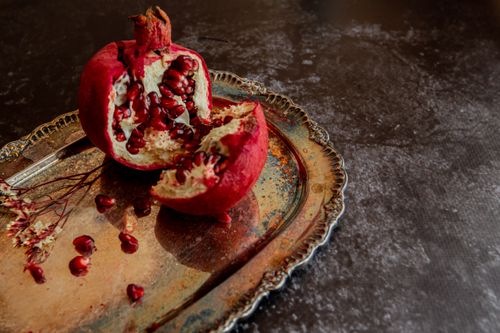 Free From above cut ripe pomegranate and seeds arranged on steel tray on black table Stock Photo