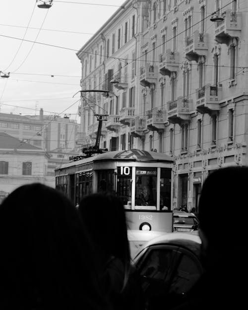 Grayscale Photography of People on Street Near Building and Tram