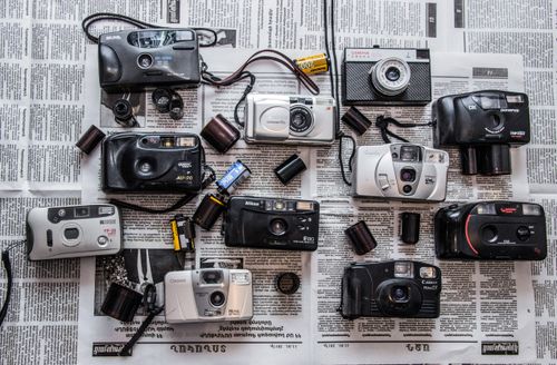 Free Flat lay of vintage cameras and film rolls on newspaper, capturing classic photography tools. Stock Photo