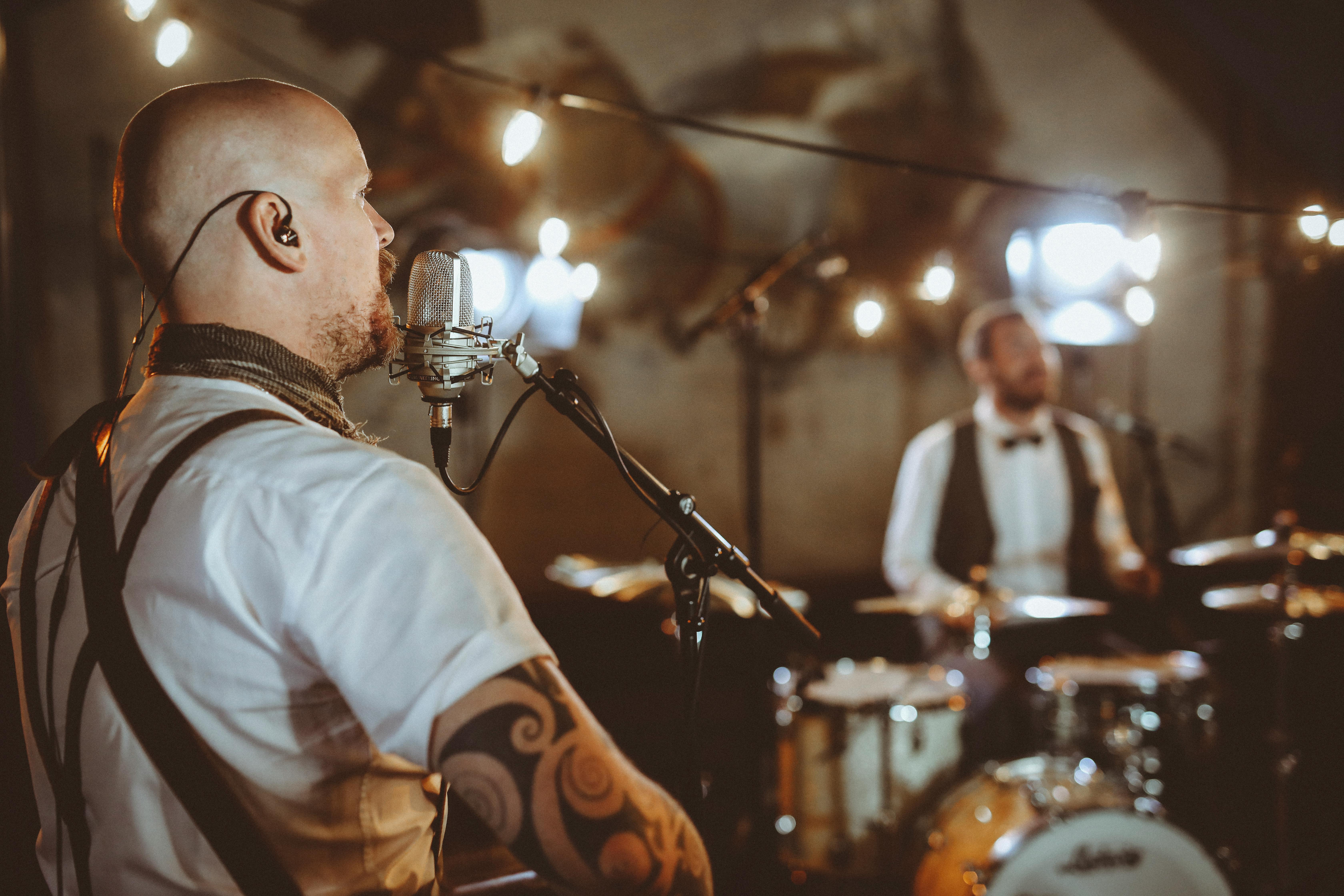 Musicians performing live in a dimly lit venue with string lights and vintage vibe.