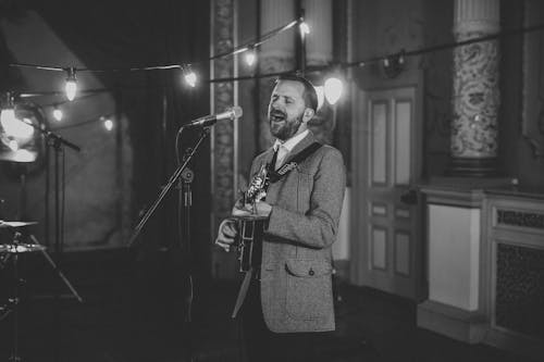 A Man Singing While Playing a Guitar