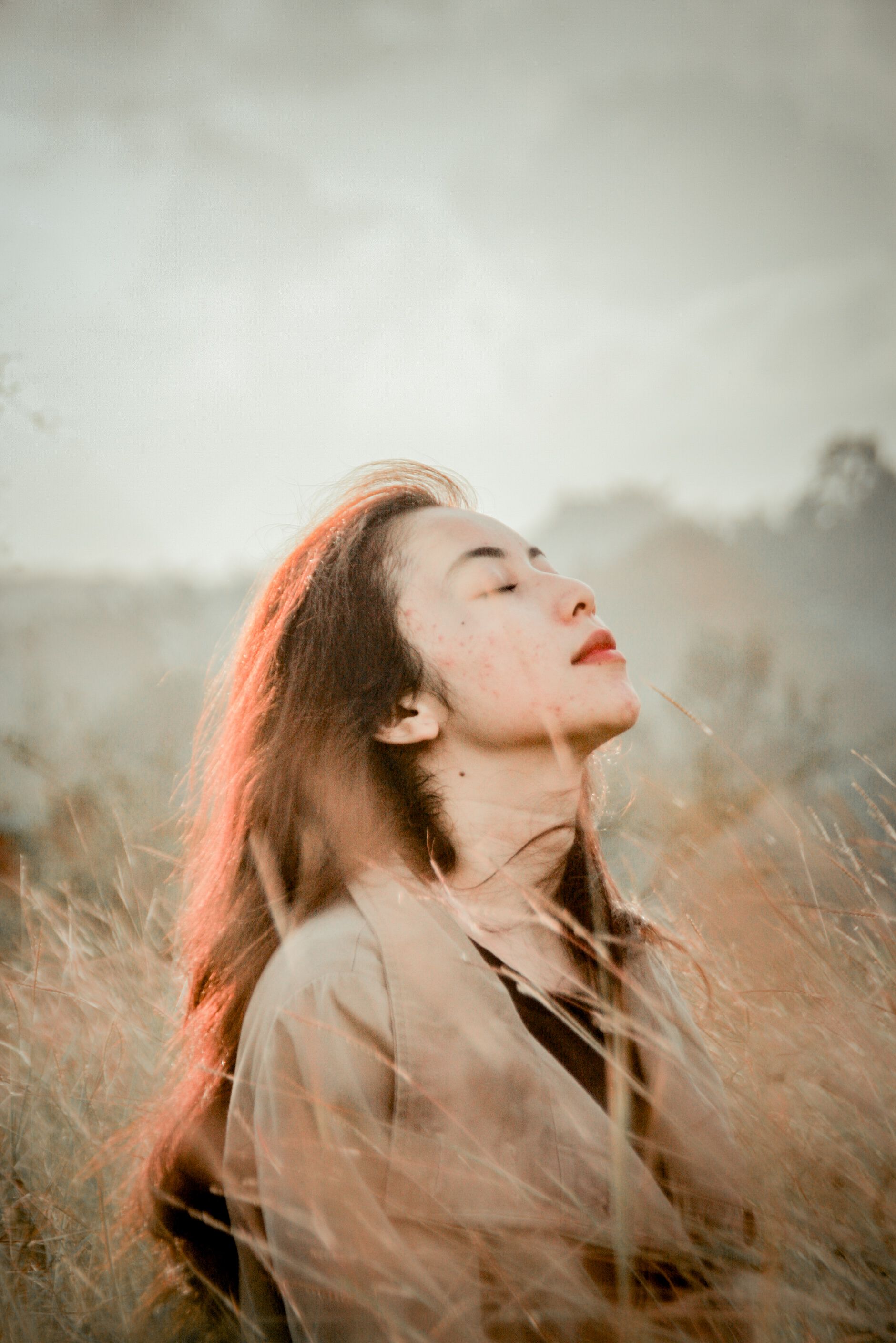 Woman in Brown Coat Standing on a Brown Grass Field · Free Stock Photo