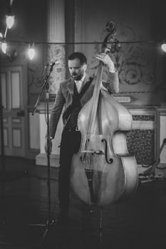 Elegant black and white photo of a musician with a double bass, evoking a vintage concert feel.