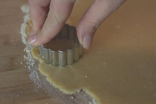 Crop person cutting dough on table