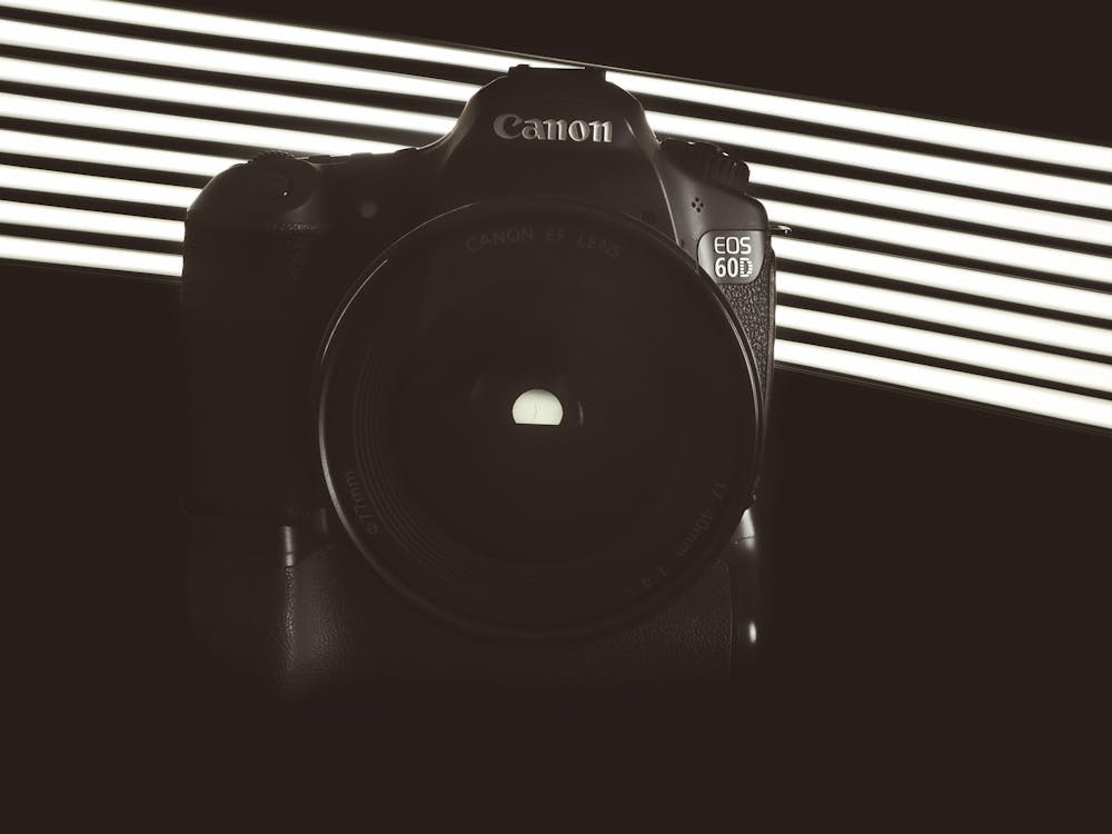 Modern digital reflex photo camera with lens placed in dark room with jalousie shadow on wall in sunlight