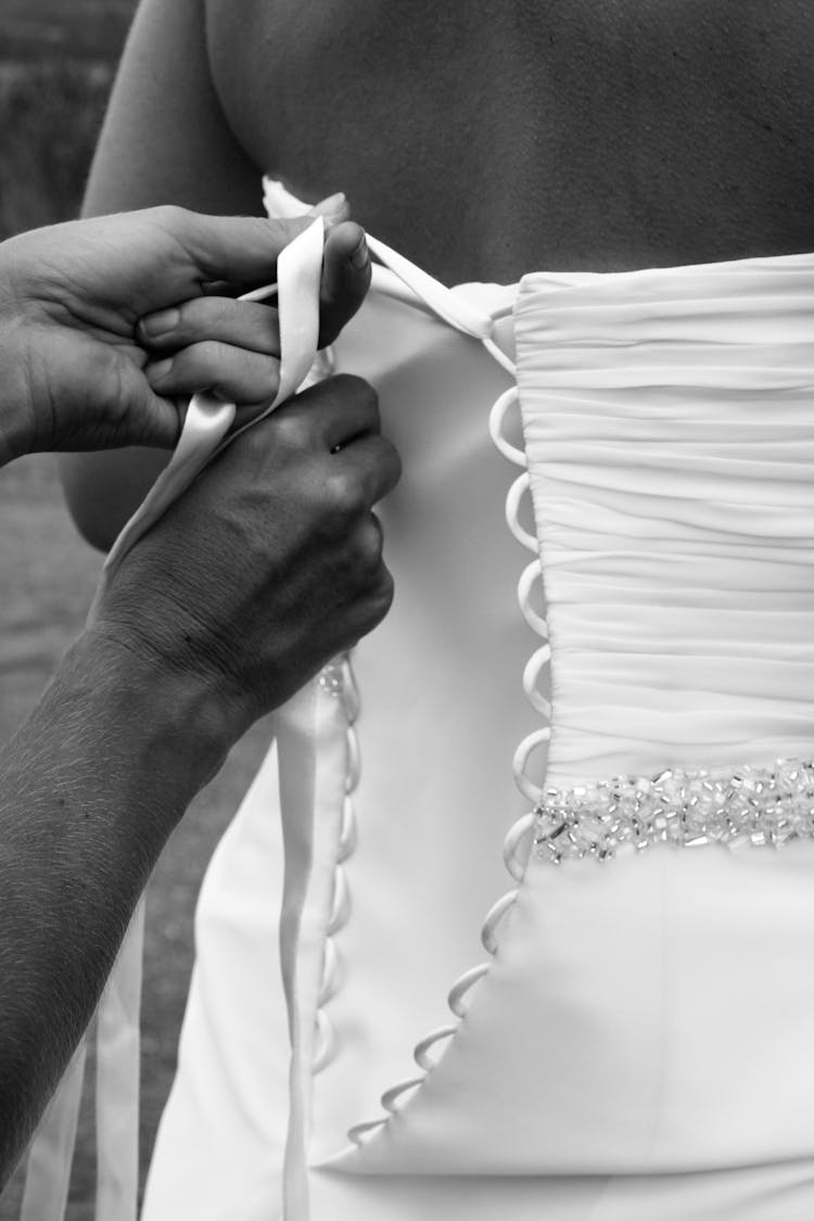 Crop Unrecognizable Bridesmaid Tying Lace On Bride Wedding Dress