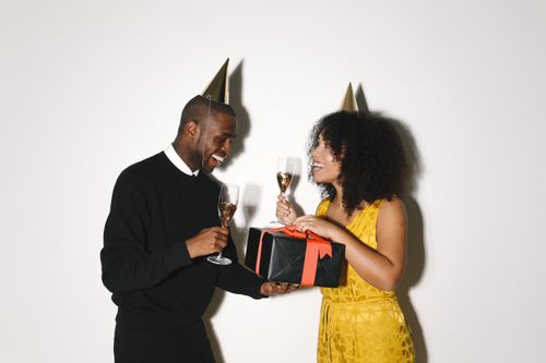 Free Happy couple exchanging gifts and toasting with champagne during a festive celebration. Stock Photo