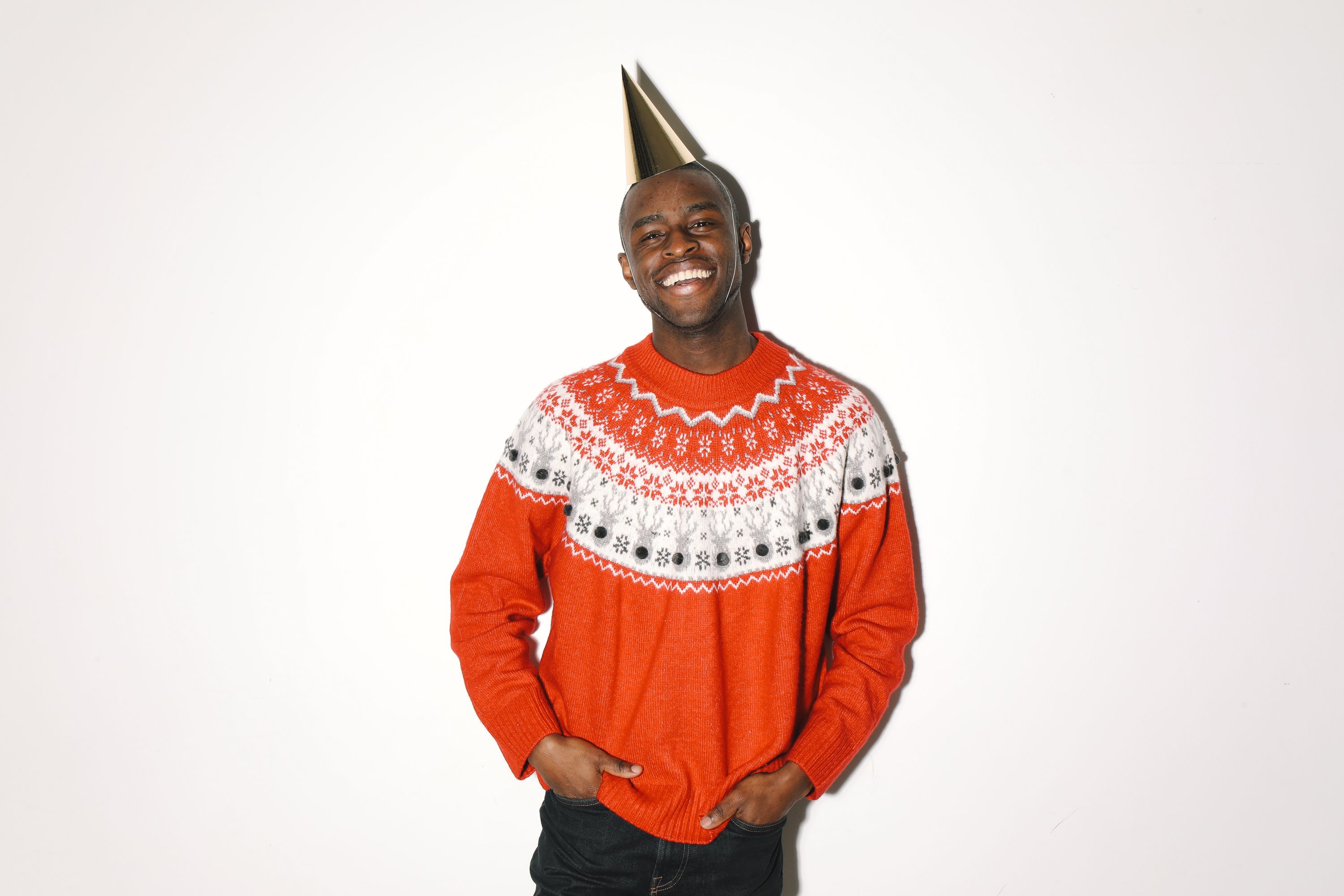 Happy man wearing a vibrant Christmas sweater and party hat, perfect for holiday celebrations.