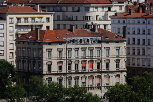 Free Aerial view of a classic European city building with a red roof and ornate facades in a sunny urban setting. Stock Photo
