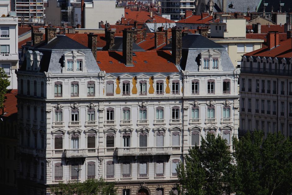 Ornate white facade of historic building with red roof tiles in Europe.