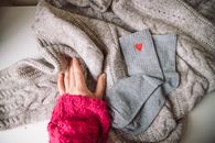 Warm knit sweater with a hand and heart-patterned socks for a cozy winter vibe.