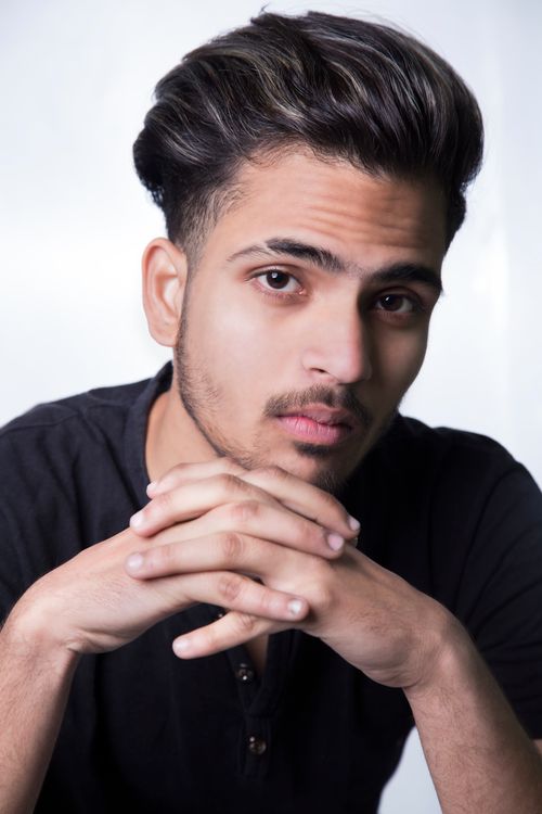 Free Close-up portrait of a young adult man posing with folded hands in a studio. Stock Photo