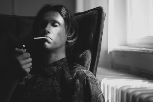 Thoughtful man lighting cigarette in room