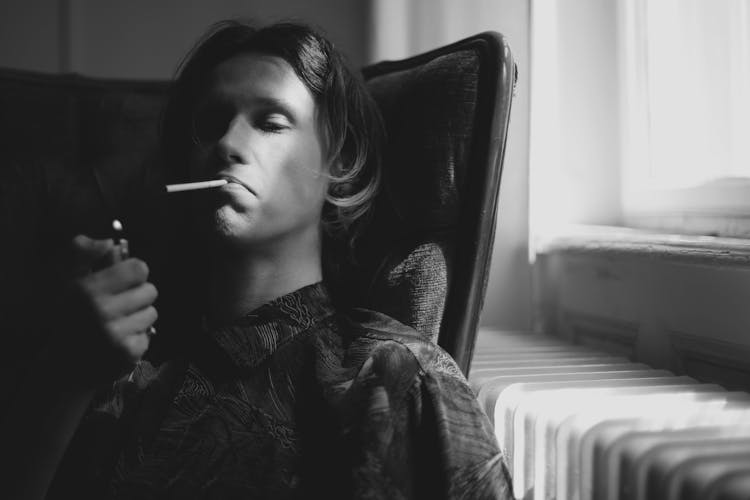 Thoughtful Man Lighting Cigarette In Room